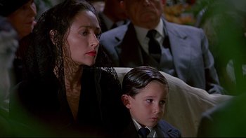 Movie still from “Psycho IV: The Beginning” (1990), directed by Mick Garris – A woman sitting next to a young boy in a suit; Close Up shot, Low angle