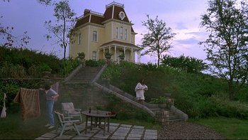 Movie still from “Psycho IV: The Beginning” (1990), directed by Mick Garris – A man standing in front of a house on a hill; Extreme Wide shot, Low angle