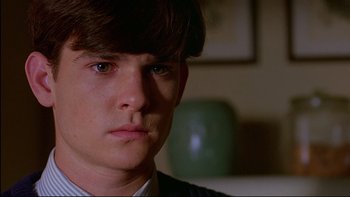 Movie still from “Psycho IV: The Beginning” (1990), directed by Mick Garris – A young man with long hair is looking at the camera; Close Up shot, Over the shoulder angle