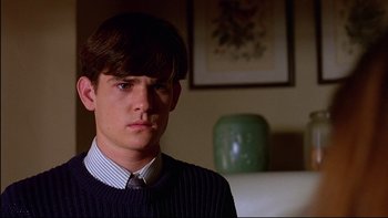 Movie still from “Psycho IV: The Beginning” (1990), directed by Mick Garris – A young man in a sweater and a tie; Close Up shot, Over the shoulder angle