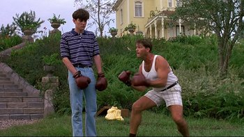 Movie still from “Psycho IV: The Beginning” (1990), directed by Mick Garris – Two young men are boxing in a yard; Medium shot, Low angle