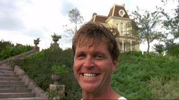 Movie still from “Psycho IV: The Beginning” (1990), directed by Mick Garris – A man smiling for the camera in front of a house; Close Up shot, Low angle