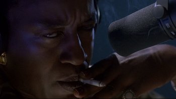 Movie still from “Psycho IV: The Beginning” (1990), directed by Mick Garris – A man smoking a cigarette while holding a microphone in front of him; Close Up shot, Low angle