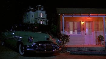 Movie still from “Psycho IV: The Beginning” (1990), directed by Mick Garris – An old car parked in front of a house at night; Wide shot, Low angle