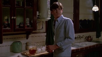 Movie still from “Psycho IV: The Beginning” (1990), directed by Mick Garris – A man standing in a kitchen next to a pitcher of tea; Medium shot, Low angle