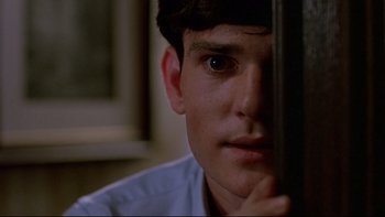Movie still from “Psycho IV: The Beginning” (1990), directed by Mick Garris – A young man is looking at the camera with his hand on his face; Close Up shot, Low angle
