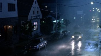 Movie still from “Psycho IV: The Beginning” (1990), directed by Mick Garris – Cars parked on the side of the road in the rain at night; Extreme Wide shot, High angle