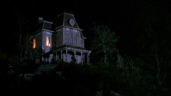 Movie still from “Psycho IV: The Beginning” (1990), directed by Mick Garris – An old house with a clock lit up at night; Extreme Wide shot, Low angle