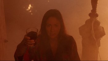 Movie still from “Psycho IV: The Beginning” (1990), directed by Mick Garris – A woman is holding a glass of wine in her hand; Medium shot, Low angle