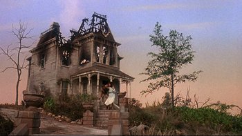 Movie still from “Psycho IV: The Beginning” (1990), directed by Mick Garris – An abandoned house with a couple sitting on the steps; Extreme Wide shot, Low angle