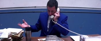 Movie still from “Punch-Drunk Love” (2002), directed by Paul Thomas Anderson – A man in a blue suit talking on a phone; Medium shot, High angle