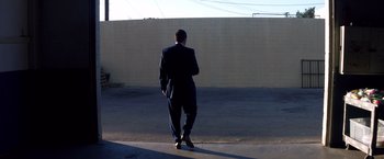Movie still from “Punch-Drunk Love” (2002), directed by Paul Thomas Anderson – A man in a suit standing in front of a wall; Wide shot, Low angle