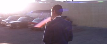 Movie still from “Punch-Drunk Love” (2002), directed by Paul Thomas Anderson – A man standing in a parking lot next to a building; Medium shot, Low angle