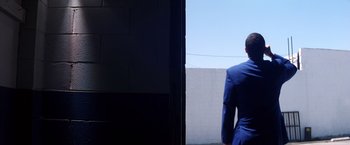 Movie still from “Punch-Drunk Love” (2002), directed by Paul Thomas Anderson – A man in a blue suit standing in front of a wall; Wide shot, Low angle