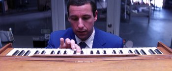Movie still from “Punch-Drunk Love” (2002), directed by Paul Thomas Anderson – A man wearing a suit and tie playing a piano; Close Up shot, High angle