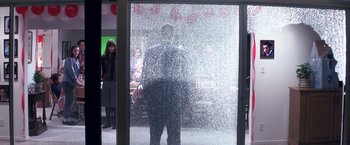 Movie still from “Punch-Drunk Love” (2002), directed by Paul Thomas Anderson – A man standing in front of a glass door; Wide shot, Over the shoulder angle