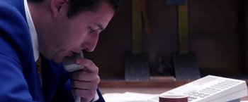 Movie still from “Punch-Drunk Love” (2002), directed by Paul Thomas Anderson – A man sitting at a table looking down at his face; Close Up shot, High angle