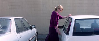 Movie still from “Punch-Drunk Love” (2002), directed by Paul Thomas Anderson – A woman standing next to a parked white car; Medium shot, Over the shoulder angle