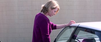 Movie still from “Punch-Drunk Love” (2002), directed by Paul Thomas Anderson – A woman standing next to a parked car looking at the window; Medium shot, Low angle