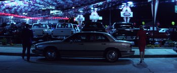 Movie still from “Punch-Drunk Love” (2002), directed by Paul Thomas Anderson – A car is driving through a parking lot; Wide shot, High angle
