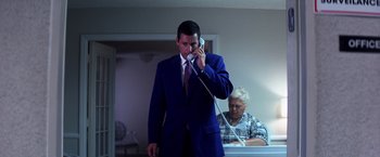 Movie still from “Punch-Drunk Love” (2002), directed by Paul Thomas Anderson – A man in a suit talking on a phone; Medium shot, Low angle