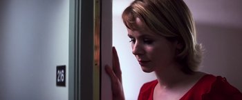 Movie still from “Punch-Drunk Love” (2002), directed by Paul Thomas Anderson – A woman in a red shirt leaning against a door; Close Up shot, Low angle