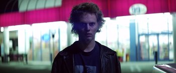 Movie still from “Punch-Drunk Love” (2002), directed by Paul Thomas Anderson – A young man with long curly hair wearing a leather jacket; Close Up shot, Low angle