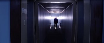 Movie still from “Punch-Drunk Love” (2002), directed by Paul Thomas Anderson – A man walking down the stairs in a dark room; Wide shot, Low angle