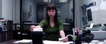 Movie still from “Punch-Drunk Love” (2002), directed by Paul Thomas Anderson – A woman sitting at a desk with papers in front of her; Medium shot, Low angle
