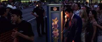 Movie still from “Punch-Drunk Love” (2002), directed by Paul Thomas Anderson – A man standing next to an electrical box on the side of the road; Medium shot, High angle