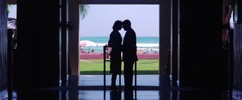 Movie still from “Punch-Drunk Love” (2002), directed by Paul Thomas Anderson – Two people are kissing in front of the ocean; Wide shot, Low angle