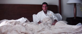 Movie still from “Punch-Drunk Love” (2002), directed by Paul Thomas Anderson – A man in a robe is laying in a bed; Medium shot, High angle