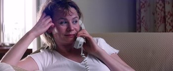 Movie still from “Punch-Drunk Love” (2002), directed by Paul Thomas Anderson – A woman talking on a phone while sitting on a couch; Close Up shot, Over the shoulder angle