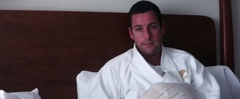 Movie still from “Punch-Drunk Love” (2002), directed by Paul Thomas Anderson – A man in a robe sitting on a bed with a pillow; Close Up shot, High angle