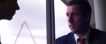 Movie still from “Punch-Drunk Love” (2002), directed by Paul Thomas Anderson – A person wearing a suit and tie; Close Up shot, Over the shoulder angle