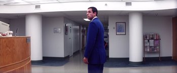 Movie still from “Punch-Drunk Love” (2002), directed by Paul Thomas Anderson – A man in a blue suit standing in a hallway; Wide shot, Low angle