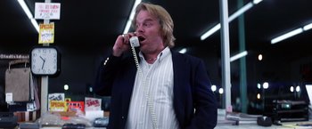 Movie still from “Punch-Drunk Love” (2002), directed by Paul Thomas Anderson – A man talking on a phone while wearing a suit; Medium shot, Low angle
