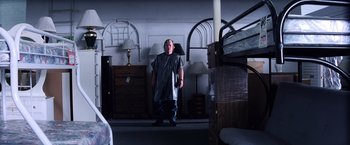 Movie still from “Punch-Drunk Love” (2002), directed by Paul Thomas Anderson – A man standing in a room wearing a gown; Wide shot, High angle