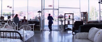 Movie still from “Punch-Drunk Love” (2002), directed by Paul Thomas Anderson – A man standing in front of an open glass door; Wide shot, High angle