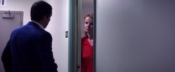 Movie still from “Punch-Drunk Love” (2002), directed by Paul Thomas Anderson – A woman in a red shirt is looking in the mirror; Medium shot, Over the shoulder angle