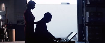 Movie still from “Punch-Drunk Love” (2002), directed by Paul Thomas Anderson – A man and a woman using a laptop computer; Medium shot, Low angle