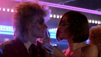 Movie still from “Purple Rain” (1984), directed by Albert Magnoli – A man and a woman are holding a drink in their hands; Close Up shot, Low angle