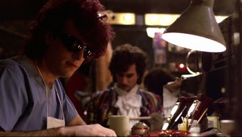 Movie still from “Purple Rain” (1984), directed by Albert Magnoli – A man sitting at a table with a cup of coffee; Close Up shot, Over the shoulder angle