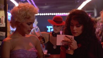 Movie still from “Purple Rain” (1984), directed by Albert Magnoli – A group of women sitting at a table looking at a piece of paper; Close Up shot, Over the shoulder angle