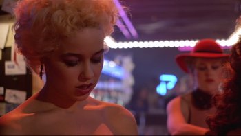 Movie still from “Purple Rain” (1984), directed by Albert Magnoli – A woman with blonde curly hair is looking at the camera; Close Up shot, Over the shoulder angle