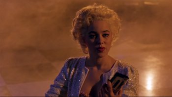 Movie still from “Purple Rain” (1984), directed by Albert Magnoli – A woman with blonde curly hair holding a cell phone; Close Up shot, Over the shoulder angle