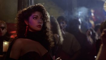 Movie still from “Purple Rain” (1984), directed by Albert Magnoli – A woman with long curly brown hair standing in front of a group of people; Close Up shot, Low angle