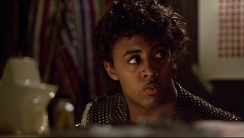 Movie still from “Purple Rain” (1984), directed by Albert Magnoli – A young man with curly black hair looking at the camera; Close Up shot, Low angle