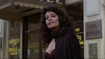 Movie still from “Purple Rain” (1984), directed by Albert Magnoli – A woman with long black curly hair wearing a red and black dress; Close Up shot, Low angle