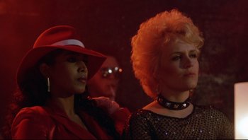 Movie still from “Purple Rain” (1984), directed by Albert Magnoli – A woman in a red hat is standing next to another woman in a black dress; Close Up shot, Low angle